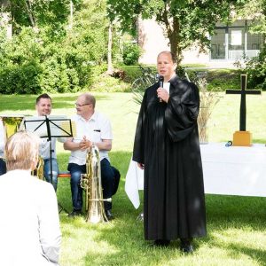 Pfarrer mit Musikern neben Altar auf grüner Wiese