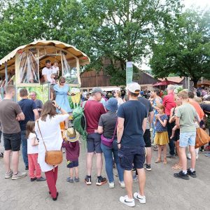 Eine Menschengruppe wartet vor einem Planwagen