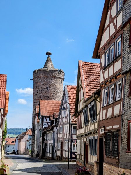 Blick in eine Gasse mit Fachwerkhäusern, weiter hinten ein Turm