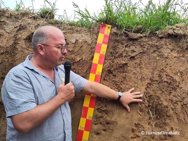 Der Landwirt Rainer Vogel zeigt auf das Bodenprofil in einem Luzernebestand