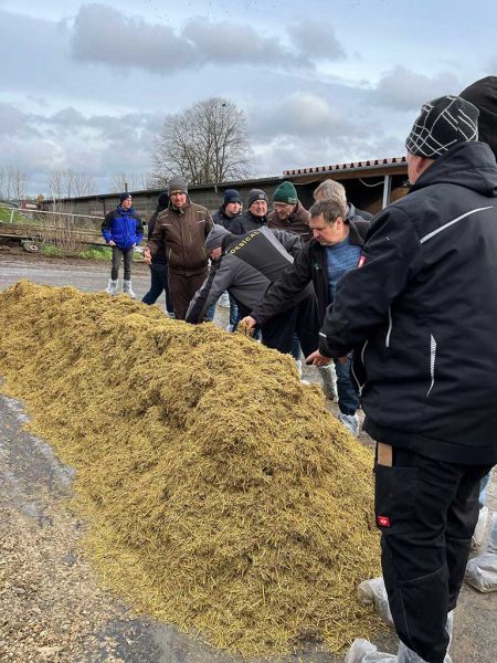 Stroh-Kalkmischung auf dem Boden, rechts daneben sind mehrere Teilnehmer des Praxistages zu sehen.