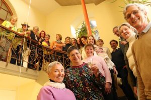 ca. 20 lächelnde Personen stehen auf einer Treppe