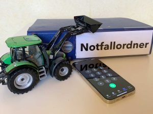 Notfallordner; im Vordergrund ein Smartphone und ein Spielzeugtrecker
