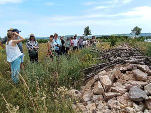 Auf der Exkursion betrachtet die Gruppe eine Eidechsenburg aus großen Steinen in der Geisenheimer Gemarkung. Frau Nicola Fischer-Quasten erklärt die Umsetzung des Naturschutzvorhabens.