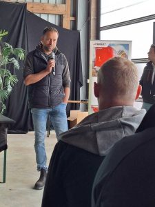 ein Referent steht mit Mikrophon in der Hand vor den Zuhörern