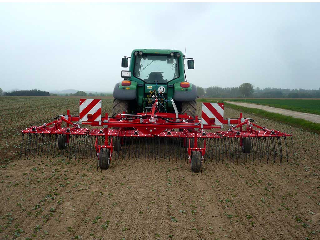 Trecker mit angehängtem Striegel auf einem Ackerbohnenfeld