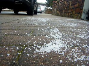 Streusalz auf einem Gehweg; im Hintergrund parkende Autos