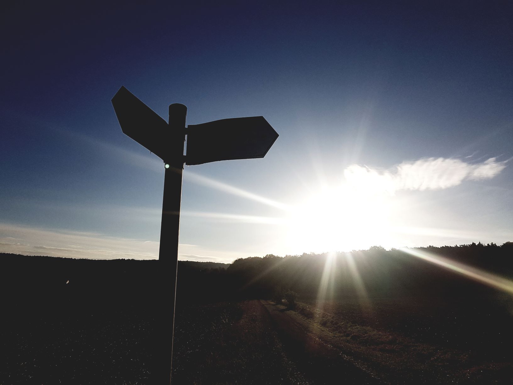 Wegweiser, der von der Sonne überstrahlt wird