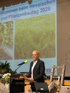 Eine Frau steht an einem Rednerpult mit Mikrofon und spricht zur Eröffnung des Hessischen Gemüse- und Pflanzenbautags.