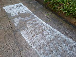 Breiter Streusalzstreifen auf einem Plattenweg