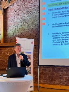 Referent mit Mikrofon und Laptop an einem Rednerpult