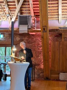 Referent mit Mikrofon und Laptop an einem Rednerpult