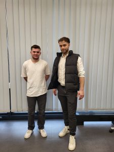 2 männliche Personen stehen in einem Raum
