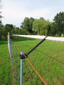Herdenschutzzaun auf einer Wiese, im Hintergrund Bäume