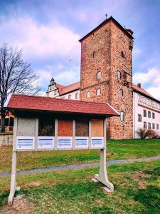 Beidseitig begehbare Ausstellungswand mit Dämmstoff-Exponaten vor dem Schloss Eichhof. Auf dieser Seite werden die Materialien Zellulose, Seegras, Recyclingkork-Granulat, Schafswolle und Flachs gezeigt, jeweils mit kurzen Informationen zu Eigenschaften und Einsatzmöglichkeiten.