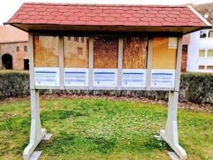 Rückseite einer beidseitig begehbaren Ausstellungswand mit Dämmstoff-Exponaten. Präsentiert werden Holzfaser, Schilf, Stroh, Hanf und Hanfjute, jeweils mit kurzen Informationen zu Eigenschaften und Einsatzmöglichkeiten.