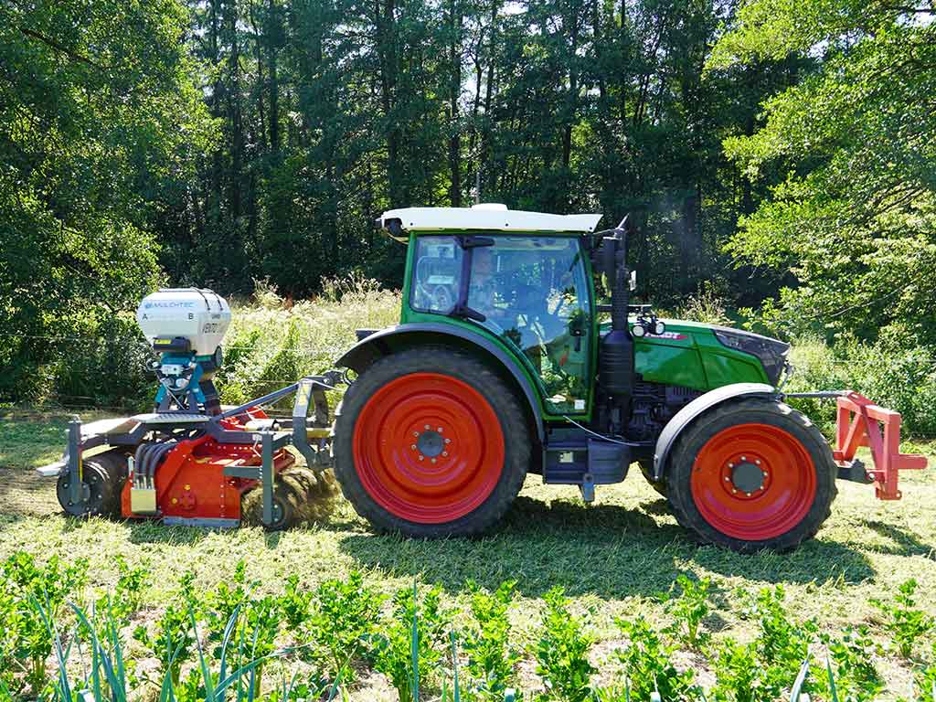 Trecker mit angehängtem MulchTec-RotoSeeder auf einer ökologisch bearbeiteten Fläche bei der Feldarbeit