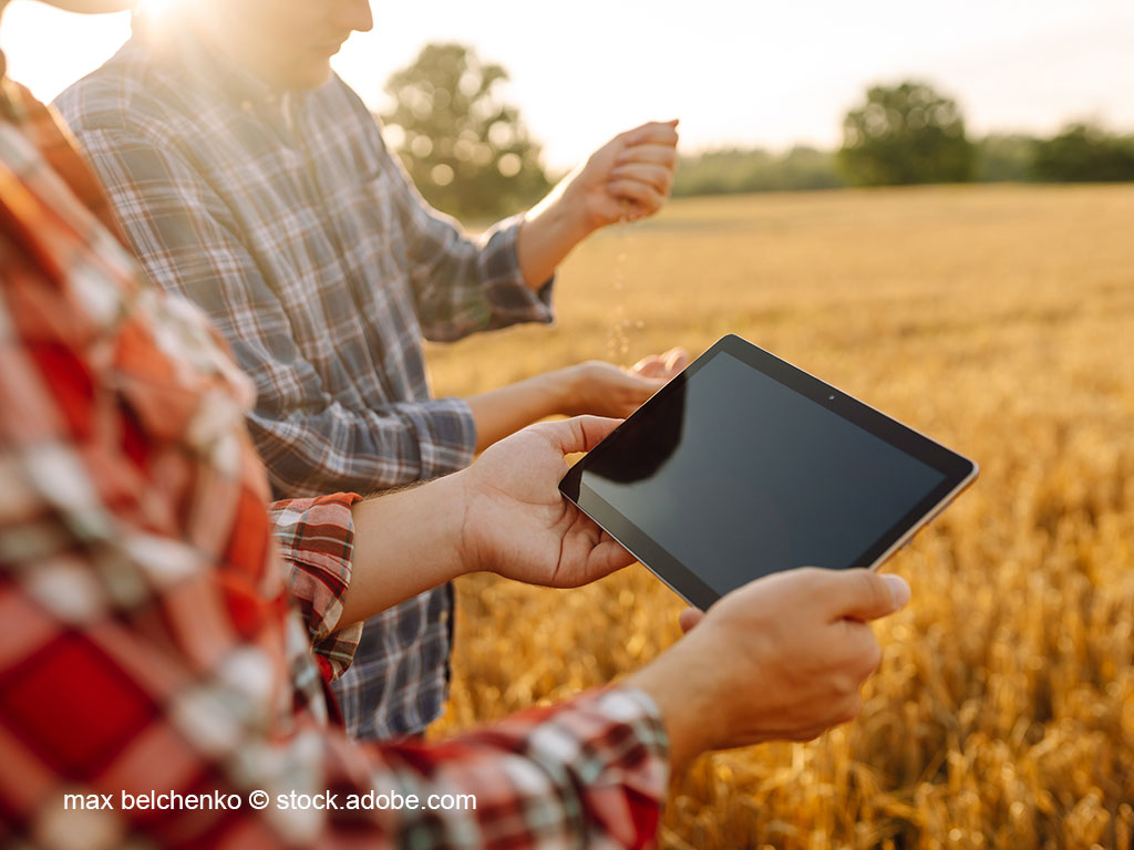 2 Landwirte begutachten eine landwirtschaftliche Fläche mittels eines Tablets