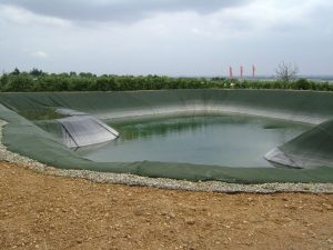 Ein Folienbecken mit grüner Folie und weißen Trocknungsrändern ist zur Hälfte mit Wasser gefüllt.
