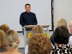 Fritz Hartmann steht am Rednerpult, davor sitzen Zuhörer.