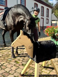 Ein echtes Pferd beschnuppert ein Holzpferd.