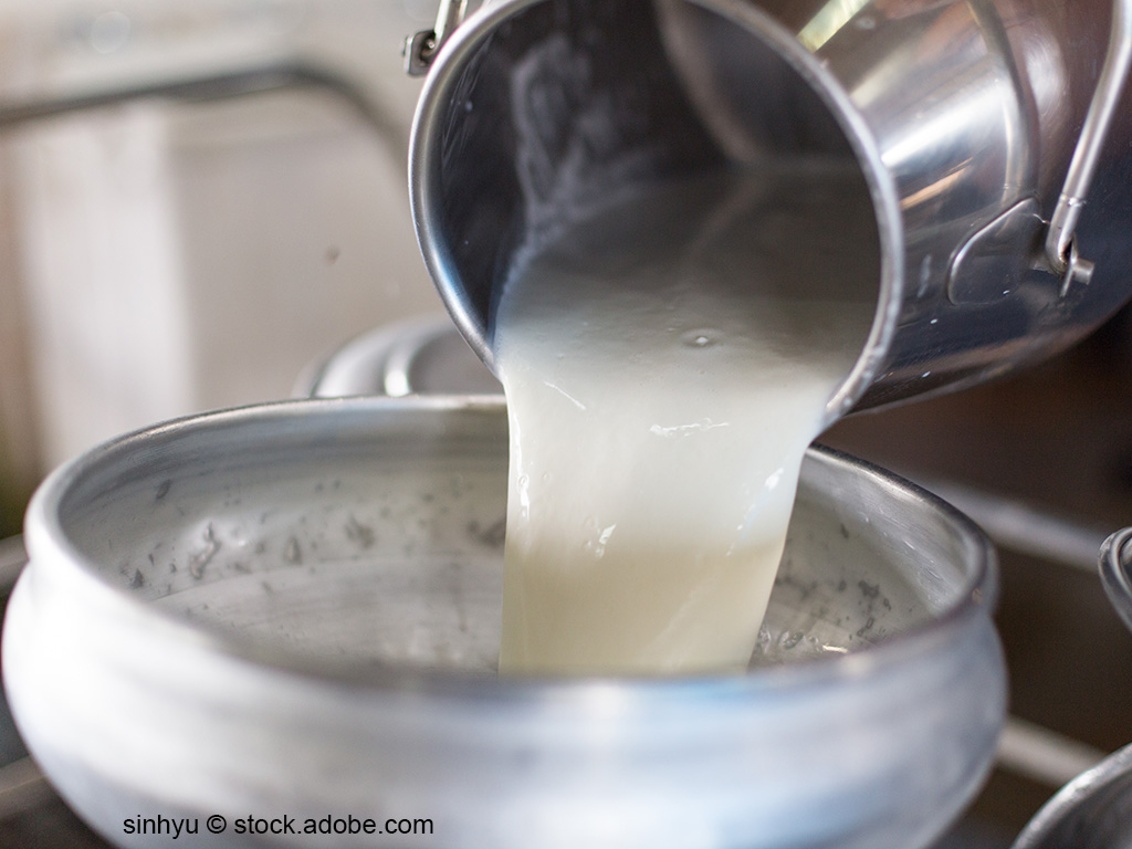 Milch wird aus einer Milchkanne umgefüllt.