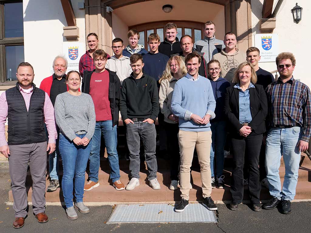 Eine Personengruppe (ca. 15 Personen) steht vor dem Eingang eines Schulgebäudes.